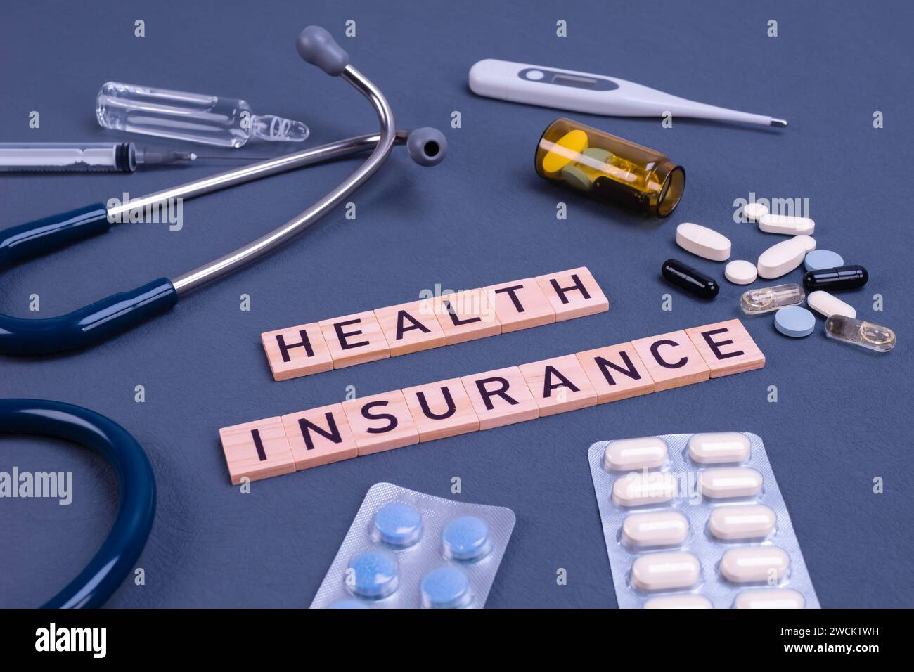 Testo di assicurazione sanitaria con stetoscopio e pillole sul tavolo. Assicurazione medica, rischio sanitario, pagare per il concetto di assistenza sanitaria. Foto Stock