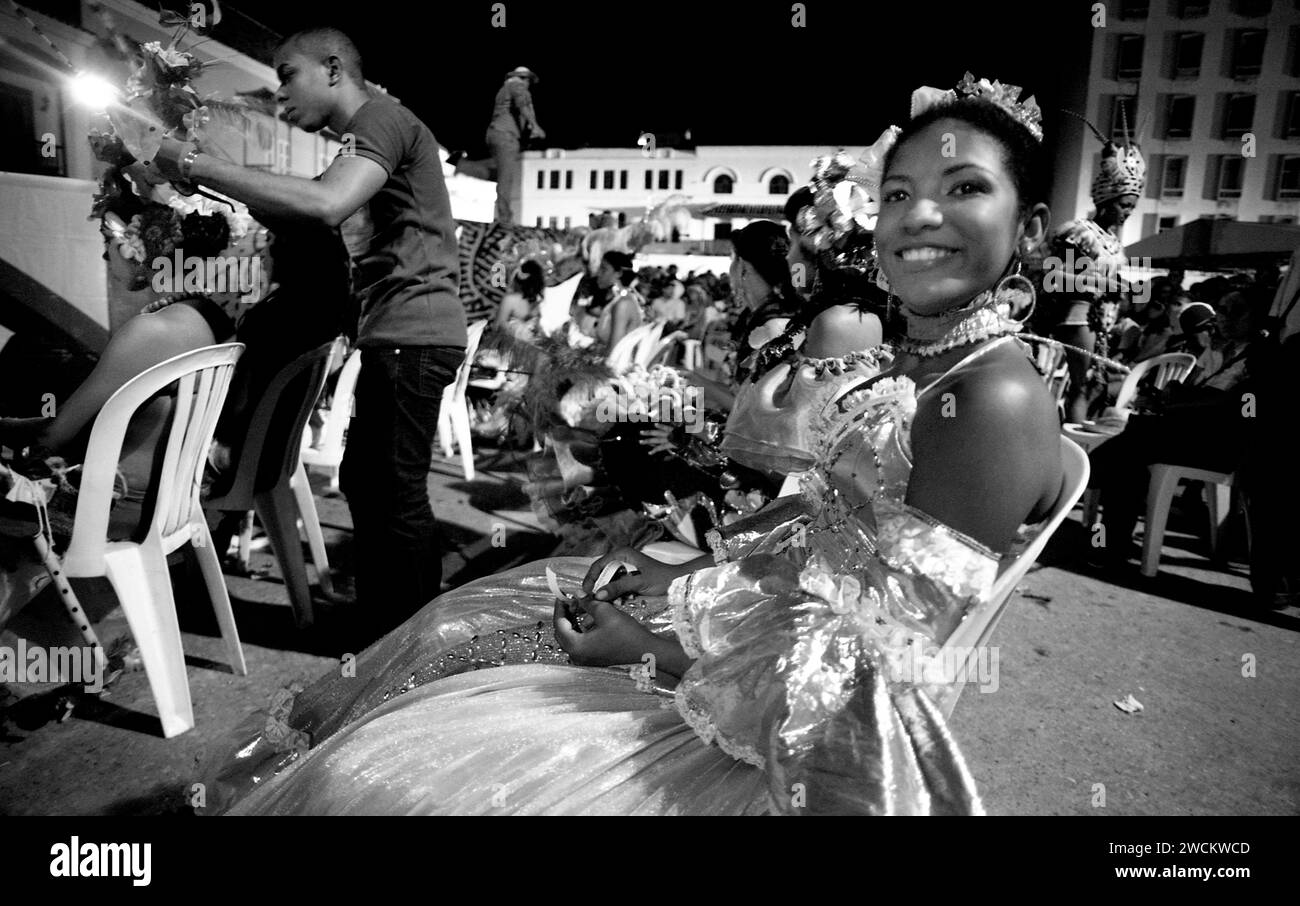 Spettacolari fotografie in bianco e nero del concorso annuale di bellezza Miss Colombia della popolazione locale a Cartagena, Colombia, i concorrenti afro-colombiani rappresentano i quartieri poveri della città. Le ragazze indossano elaborati costumi fatti in casa e copricapi di piume e sfilano le strade secondarie di Cartagena dopo il tramonto. Foto Stock