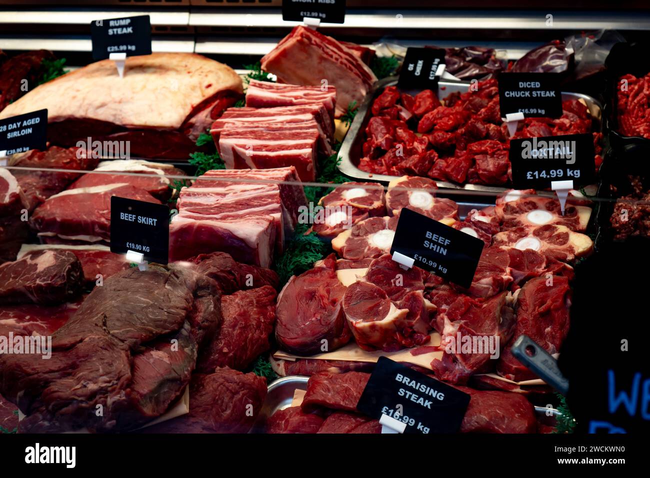 Un'esposizione di vari tagli di manzo in una macelleria di Saffron Walden, Essex, tra cui bistecca di manzo e coda di bue. Foto Stock