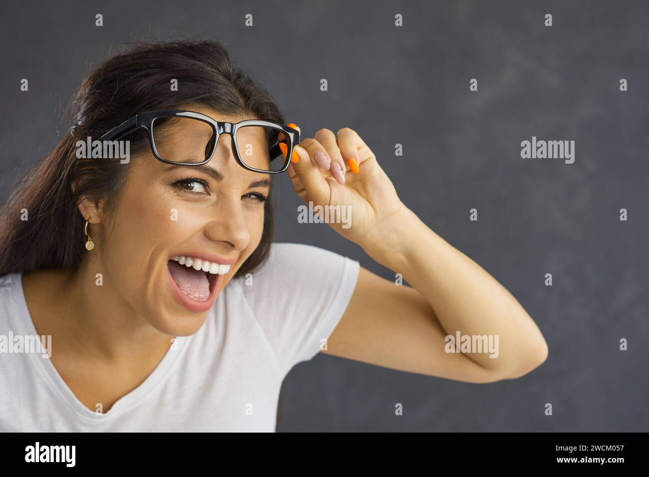 Primo piano del volto divertente della giovane ed emotiva donna caucasica su sfondo grigio. Foto Stock