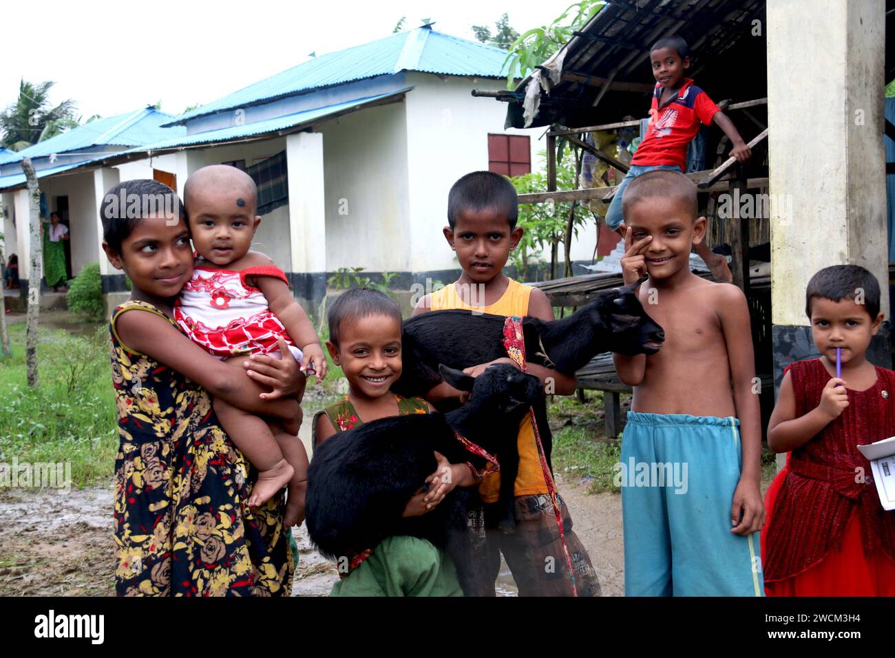 I bambini del Bangladesh rurale giocano felicemente nel quartiere con le capre. Gucchogram, Jhinaigati, Sherpur. Bangladesh. Foto Stock