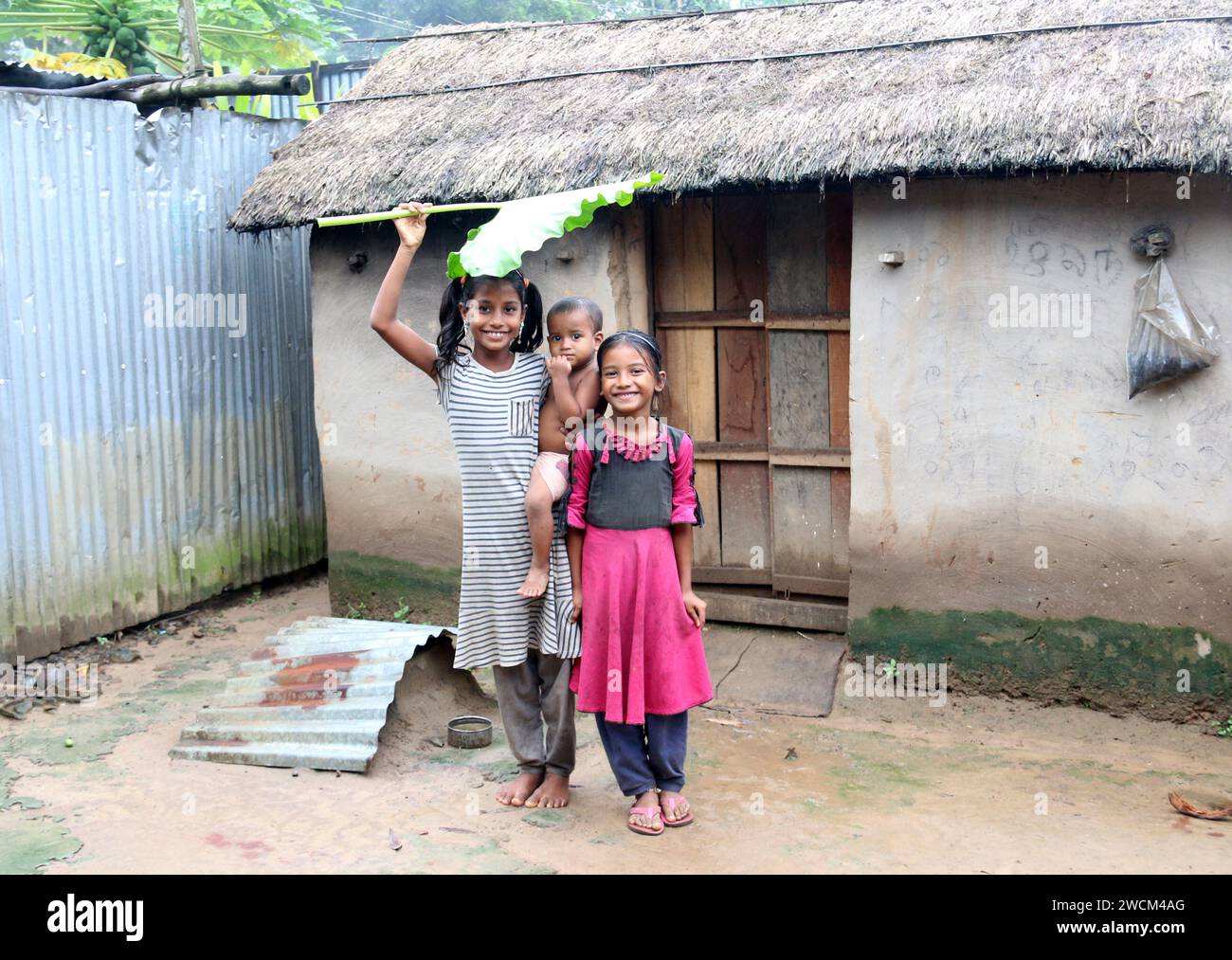 I bambini rurali del Bangladesh si mettono in posa per una foto mentre si coprono la testa con una grande foglia per evitare il sole. Gucchogram, Jhinaigati, Sherpur. Bangladesh. Foto Stock