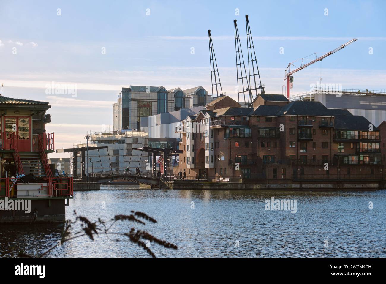 Molo interno di Millwall, affacciato a sud verso Glengall Bridge, Pepper Street, con gru storiche e moderne. Giornata di sole, cielo blu Foto Stock