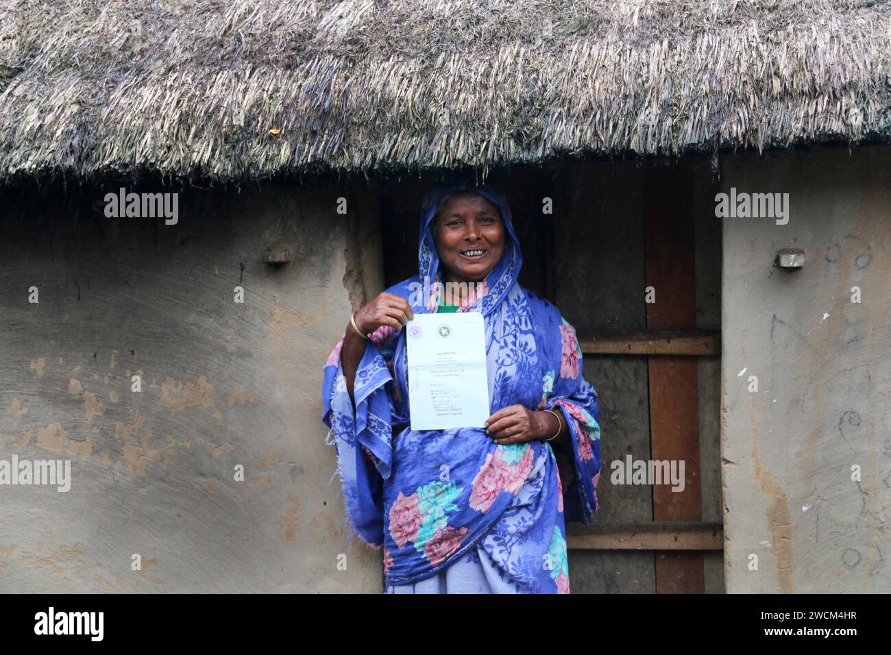 Ritratto di una donna rurale del Bangladesh che mostra il suo alloggio e le indennità di vecchiaia donate dal governo. Jhinaigati, Sherpur. Bangladesh. Foto Stock