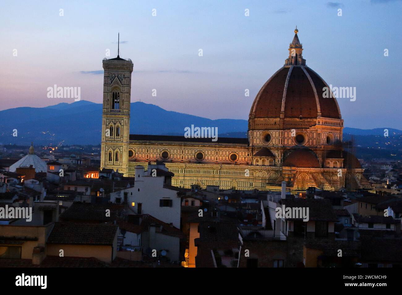 Il Duomo di Firenze sopra i tetti della città, durante la prima serata con illuminazione artificiale Foto Stock