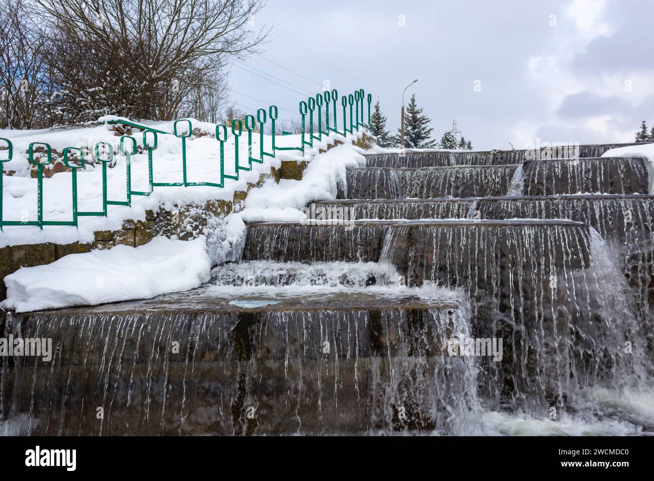 Paesaggio invernale con ruscello e cascata in un parco cittadino in Europa Foto Stock