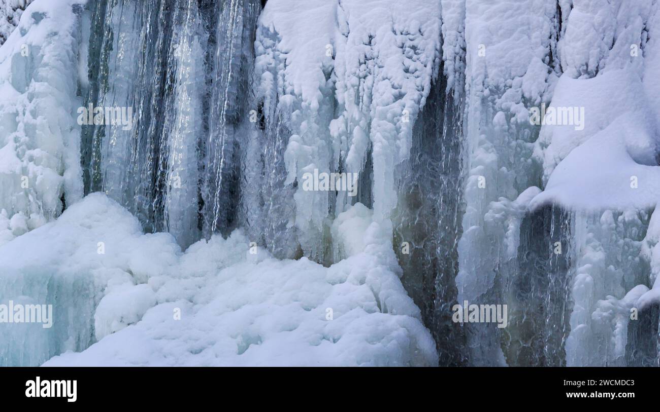 Paesaggio invernale con ruscello e cascata in un parco cittadino in Europa Foto Stock