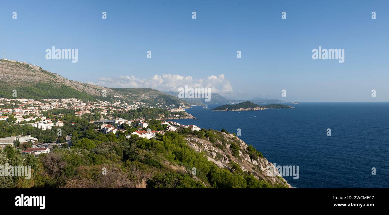 Vista panoramica della costa di Dubrovnik, con le sue acque cristalline e verdi scogliere lussureggianti, sotto un cielo punteggiato di nuvole. Foto Stock