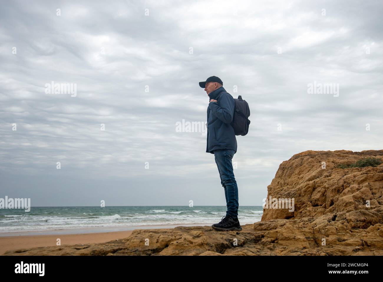 Escursionista maschile con zaino in piedi per godersi la vista dell'oceano Foto Stock