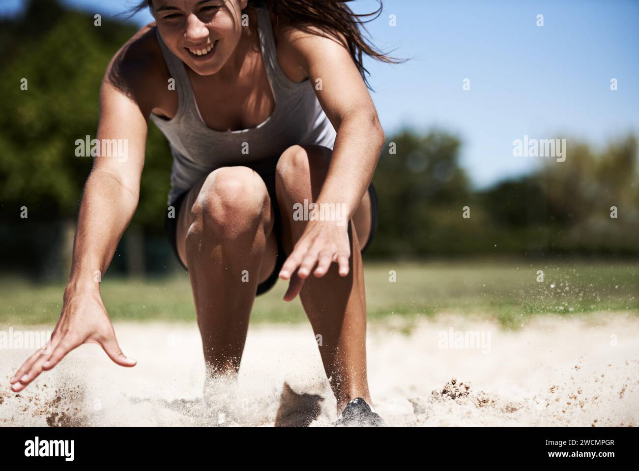 Atleta donna, sabbia e salto lungo allenata all'aperto per gare di resistenza, abilità o prestazioni. Persona femminile, viso e obiettivo fitness per l'allenamento cardiovascolare Foto Stock