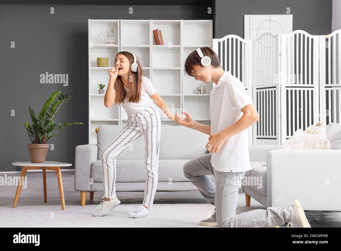Ragazza carina con suo fratello che ascolta musica e balla a casa Foto Stock