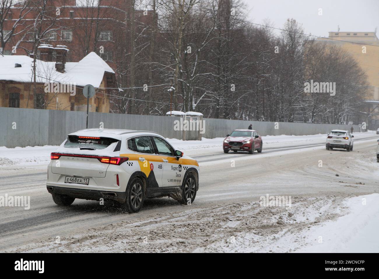 Un'auto passeggeri Yandex taxi guida lungo una strada scivolosa coperta di neve su Kremenchugskaya Street durante le forti nevicate, in inverno. Foto Stock