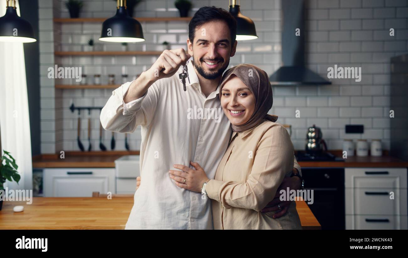 Giovane coppia appena sposata in cucina sorride guarda il marito della macchina fotografica mostra un mucchio di chiavi della nuova casa. Orgogliosi proprietari di case, affittato appartamento, prestito mor Foto Stock