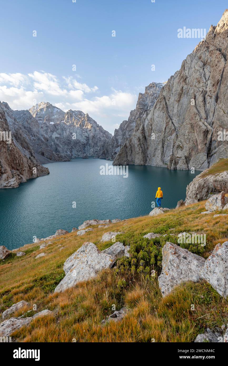 Turista presso il lago di montagna blu tra le ripide vette rocciose, il lago Kol Suu, i monti Sary Beles, la provincia di Naryn, il Kirghizistan Foto Stock