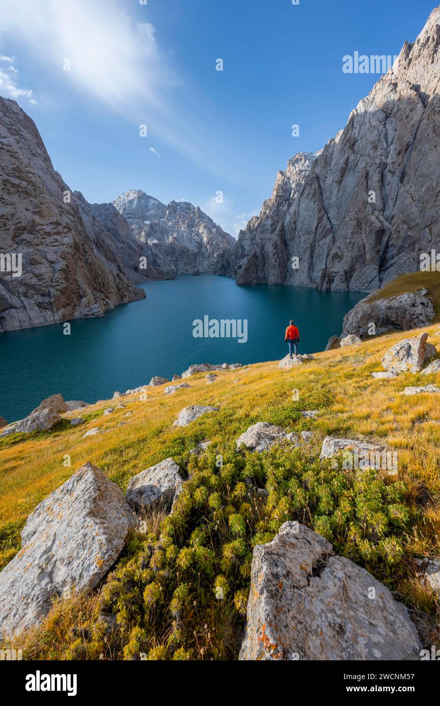 Turista presso il lago di montagna blu tra le ripide vette rocciose, il lago Kol Suu, i monti Sary Beles, la provincia di Naryn, il Kirghizistan Foto Stock