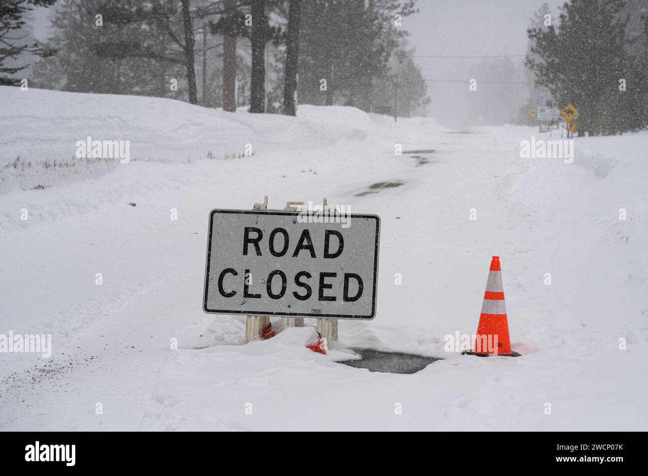 Cartello "strada chiusa" durante l'evento atmosferico di tempesta invernale sul fiume nelle montagne della Sierra Nevada. Foto Stock