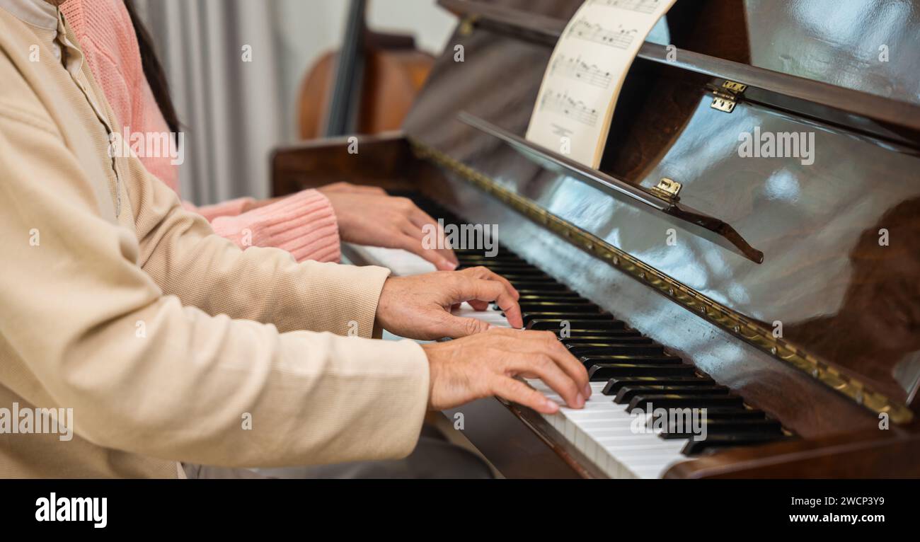 Giovane donna che insegna pianoforte per l'insegnamento di alto uomo Foto Stock