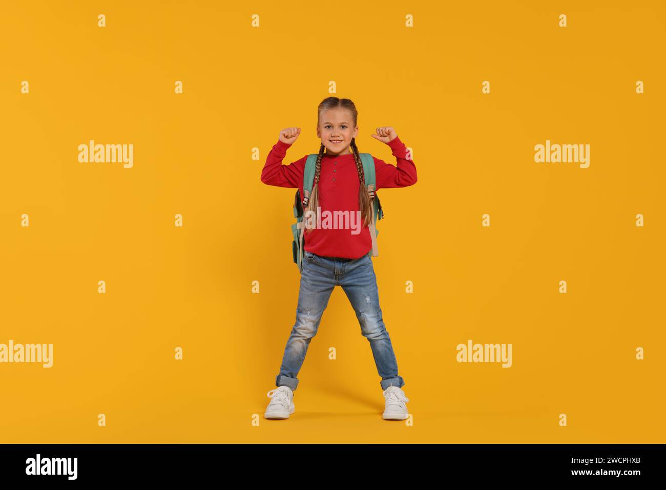 Studentessa felice con lo zaino su sfondo arancione Foto Stock