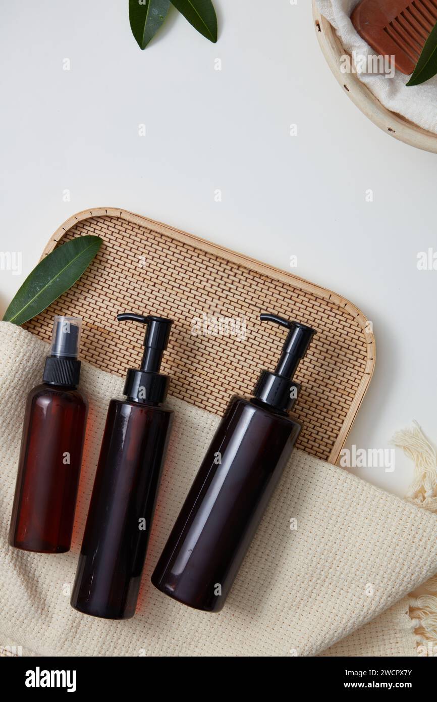 Vassoio di bambù con tre bottiglie vuote con etichetta e una sciarpa di lana. Promuovendo detergenti, shampoo, schiume o prodotti di lozione Foto Stock
