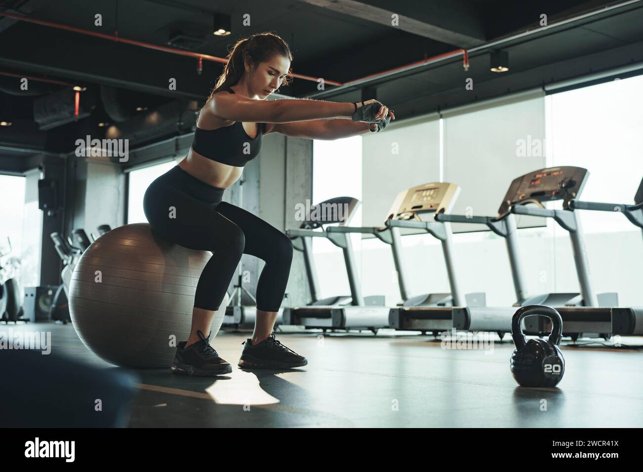 Donna sportiva che si allena e utilizza il fitball seduti e bilanciati. Foto Stock