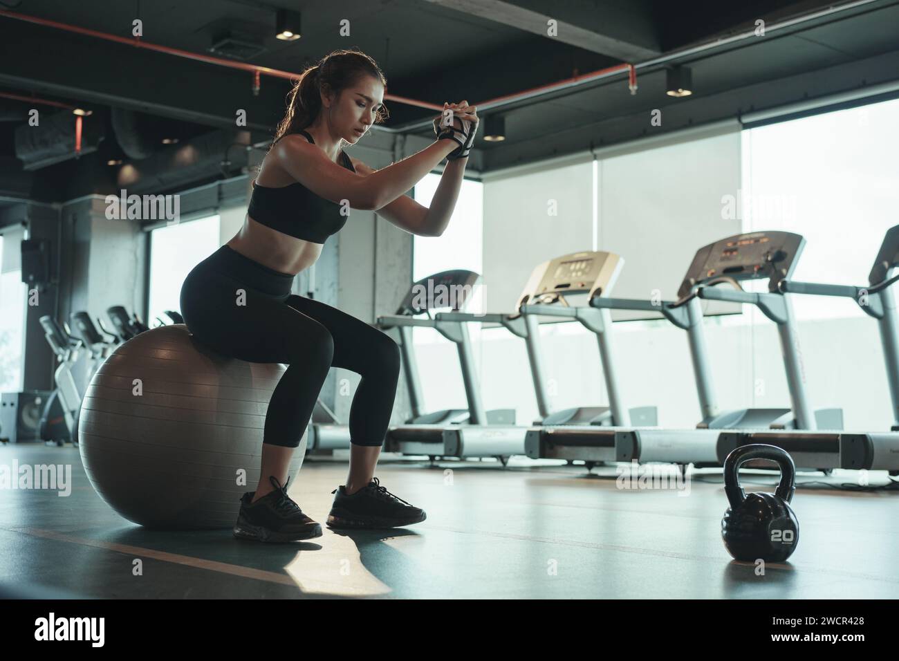 Donna sportiva che si allena e utilizza il fitball seduti e bilanciati. Foto Stock