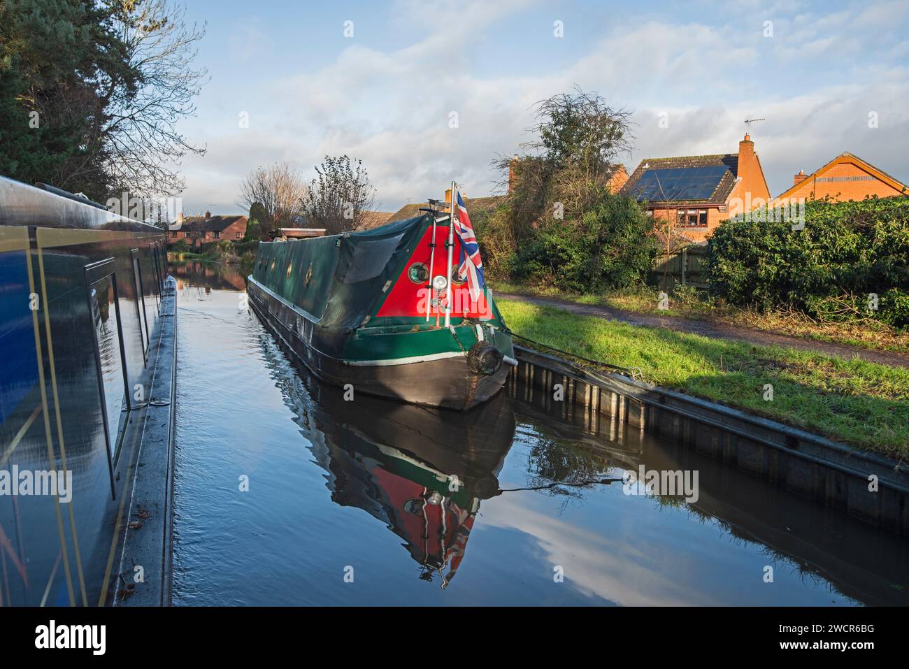 Vista da un narrowboat che viaggia nel paesaggio urbano della campagna inglese sul canale navigabile britannico attraverso il villaggio Foto Stock