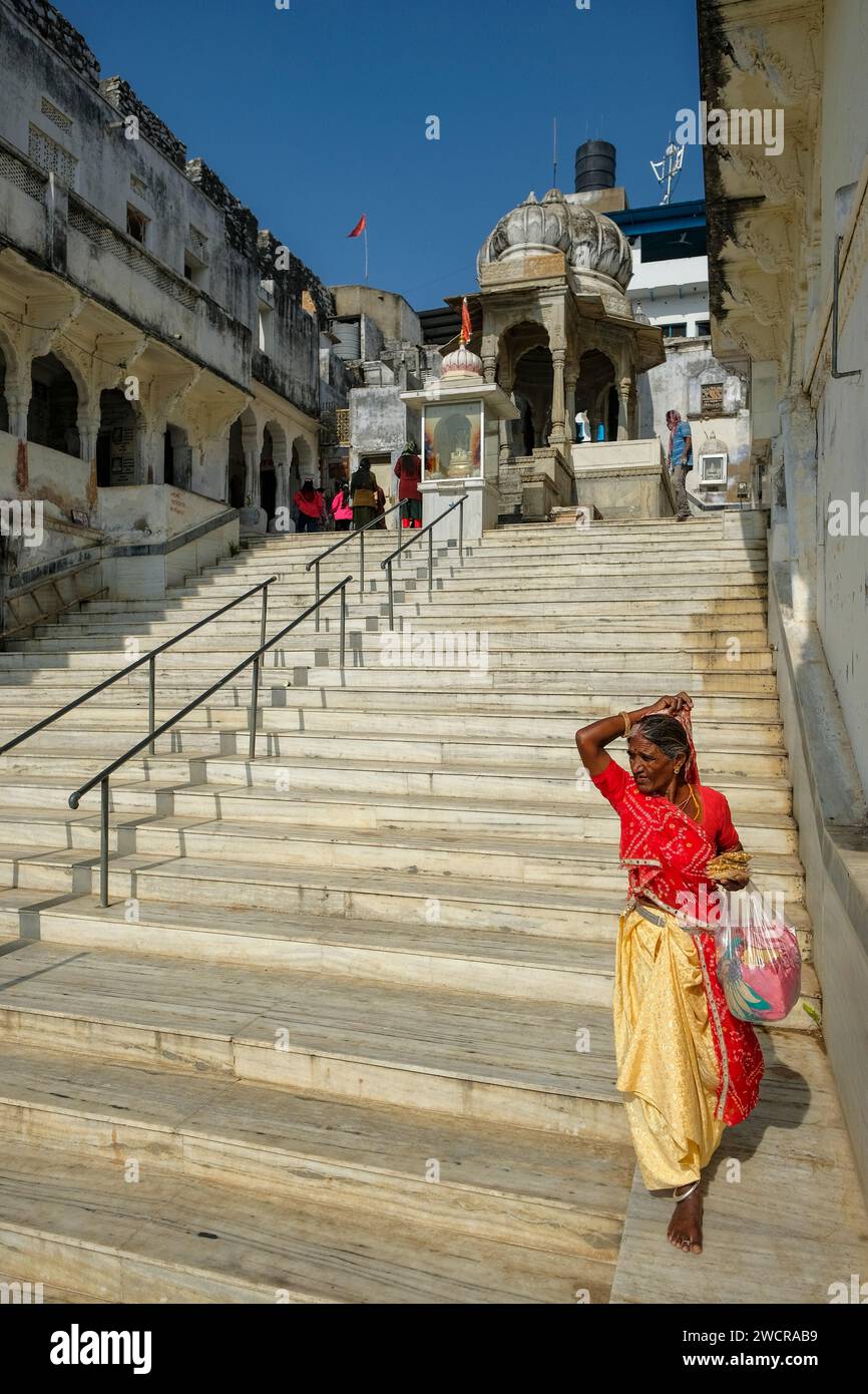 Pushkar, India - 4 gennaio 2024: Una donna che cammina lungo un ghat del lago Pushkar nel Rajasthan, India. Foto Stock