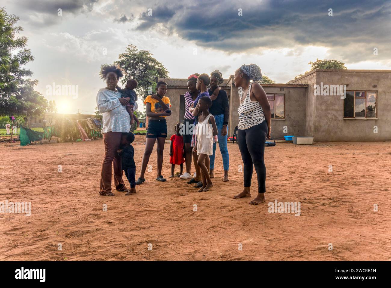 famiglia africana nel villaggio che si gode il tramonto nel cortile dopo una buona pioggia Foto Stock