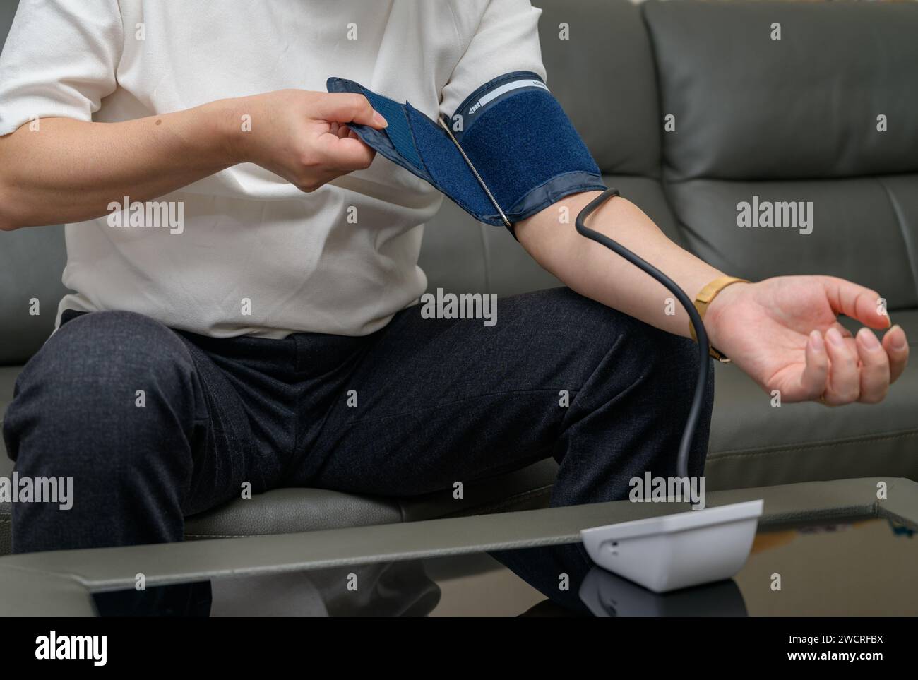 Uomo di mezza età che usa il misuratore della pressione sanguigna Foto Stock