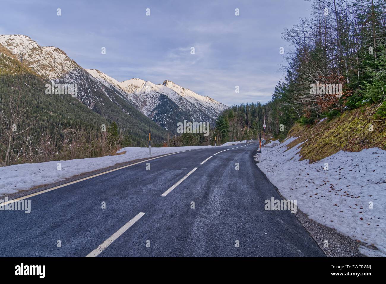 Una strada di montagna innevata che mostra la serenità e la bellezza dei paesaggi invernali Foto Stock
