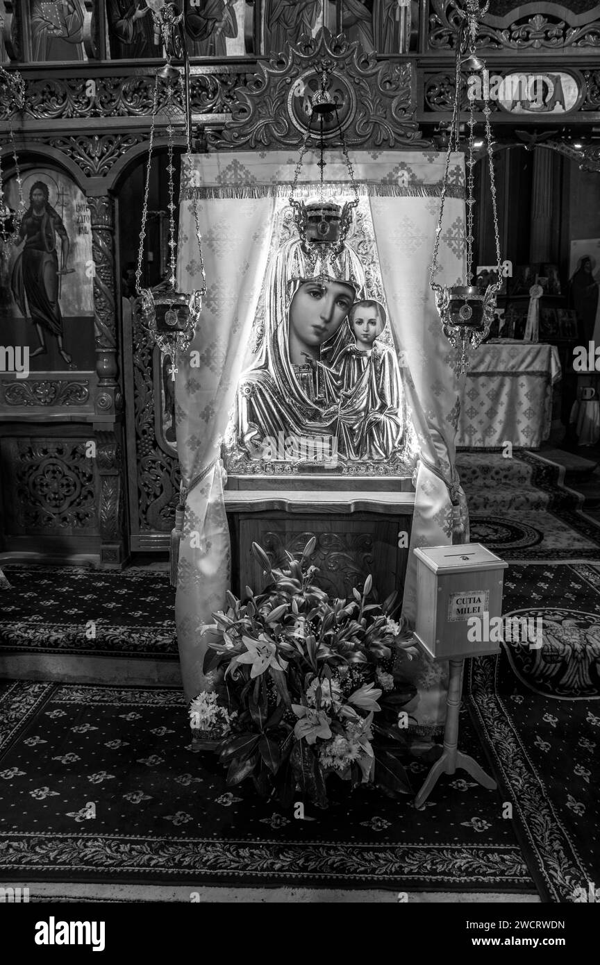 Altare con la statua della Madonna adornata con composizioni floreali e candele nella chiesa ortodossa Foto Stock
