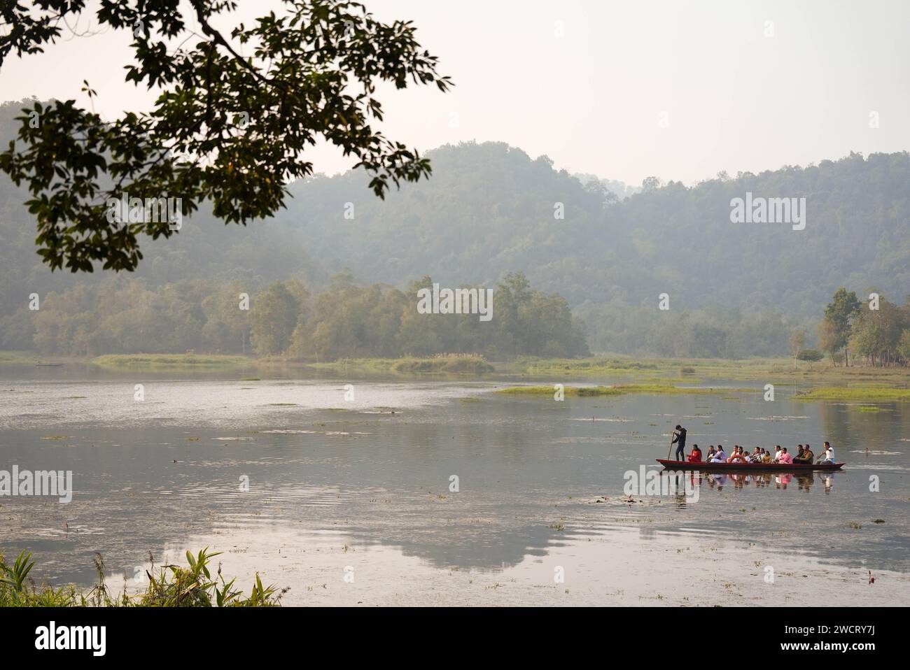 Un gruppo di persone che si godono una piacevole gita in barca nel tranquillo lago circondato da alberi Foto Stock