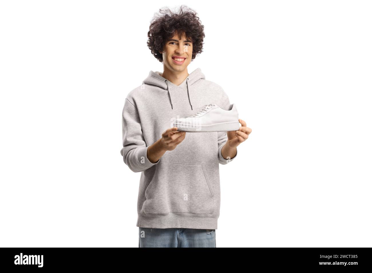 Giovane uomo felice che tiene in mano una sneaker bianca isolata su sfondo bianco Foto Stock