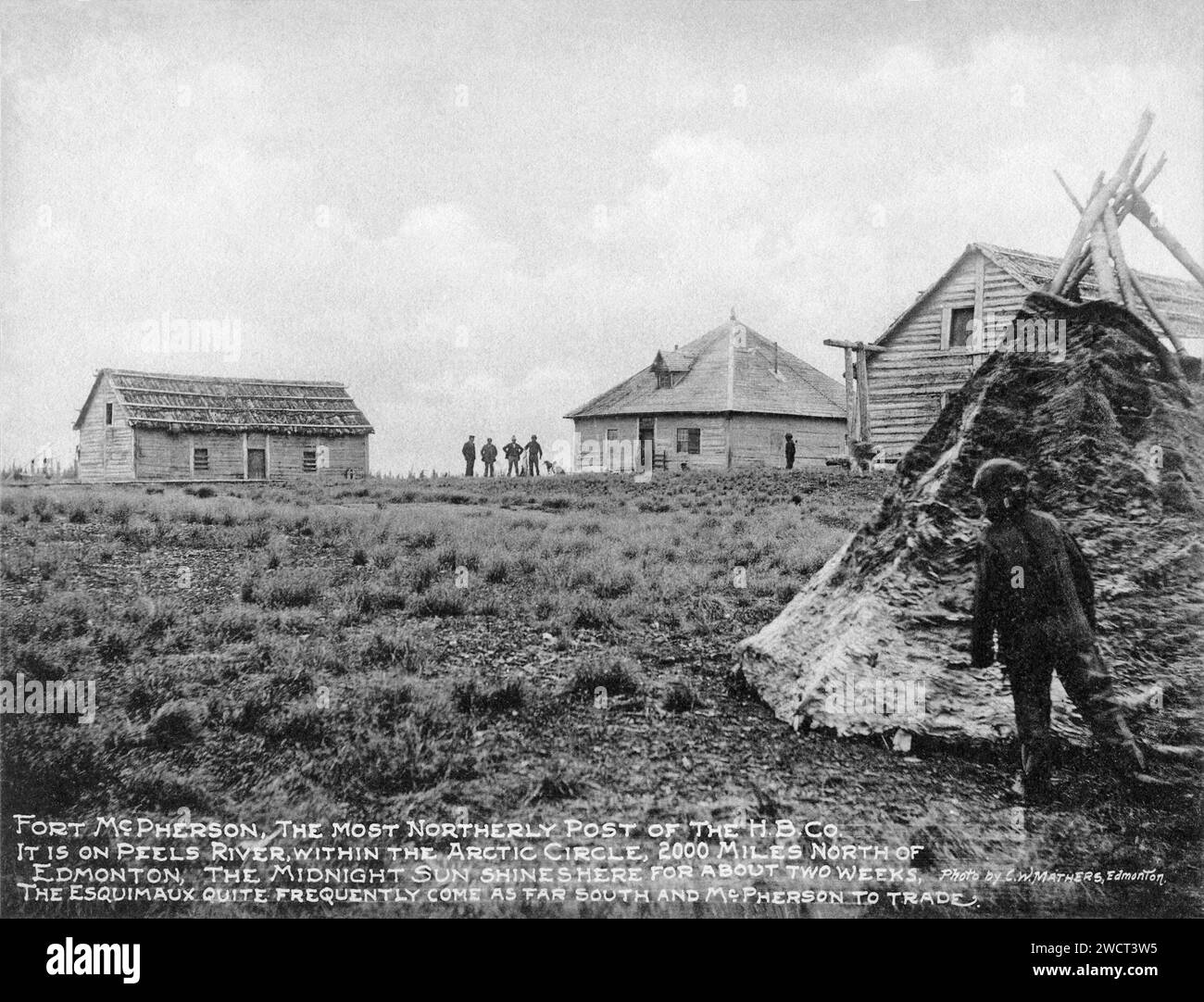 Una fotografia del 1901 di Fort McPherson, un post della compagnia della Baia di Hudson sul fiume Peel nei territori del Nord-Ovest, scattata da C W Mathers in una spedizione nell'estremo nord del Canada e pubblicata nel suo libro "l'estremo Nord". Mathers didascalò questa foto: Fort McPherson, il posto più settentrionale della H.B.Co.. Si trova sul fiume Peel, all'interno del Circolo Polare Artico, 2000 miglia a nord di Edmonton, il sole di mezzanotte splende qui per circa due settimane. Gli Esquimaux (Inuit) arrivano abbastanza spesso a sud e McPherson per il commercio. Foto Stock