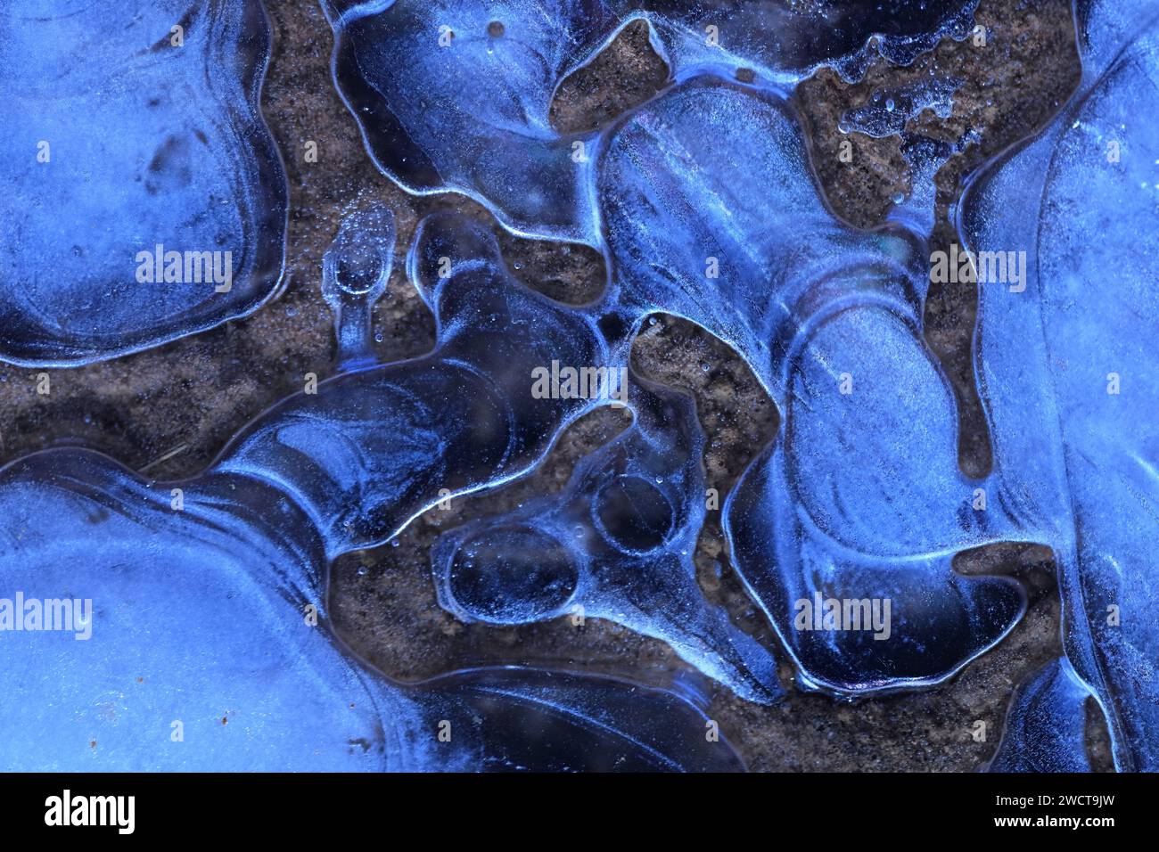 Motivi astratti di ghiaccio blu con un accenno di roccia bruna, rivelando l'intricata bellezza della prima gelata invernale Foto Stock