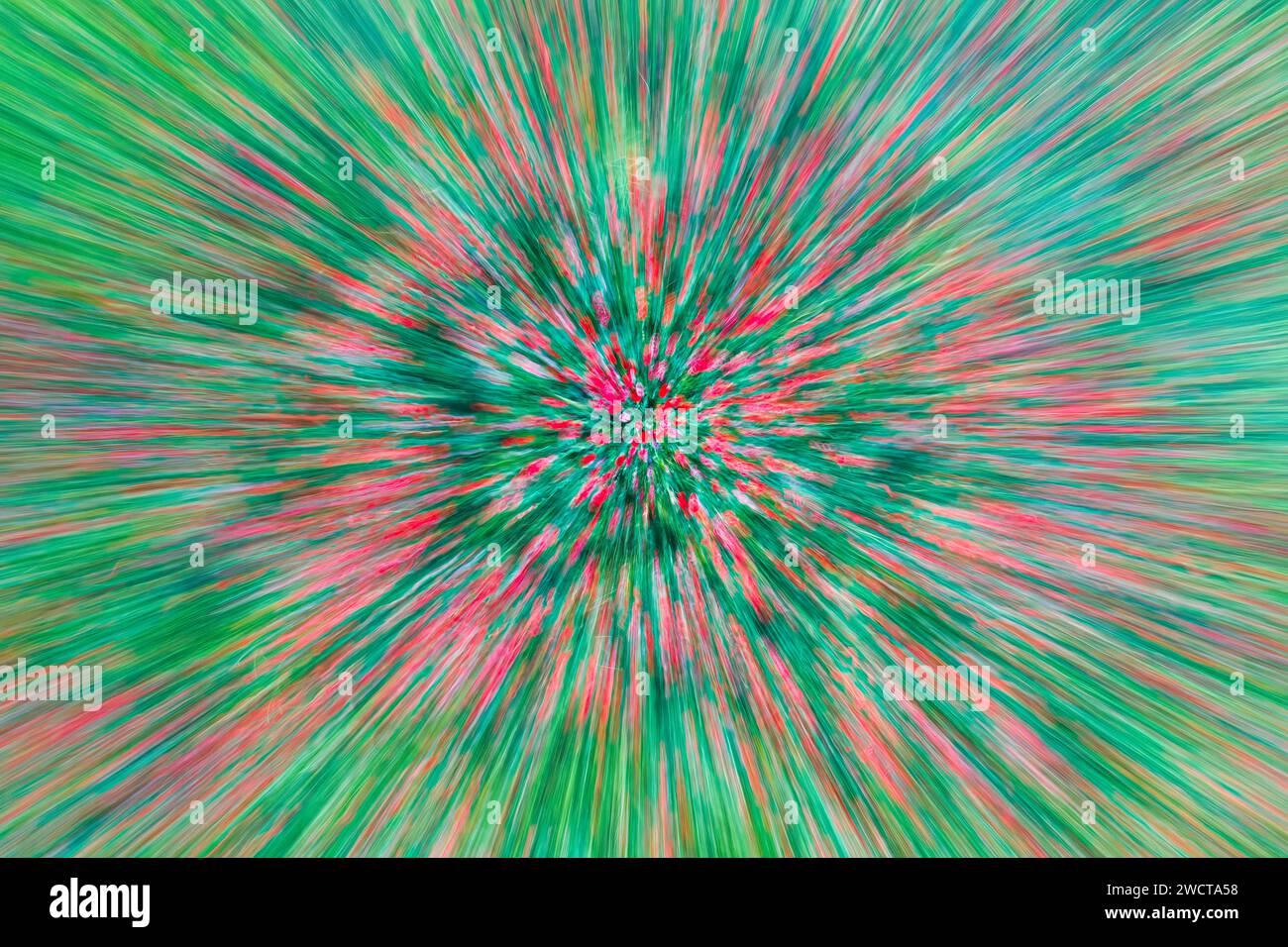 Immagine astratta di un campo con un effetto di sfocatura radiale che crea una vivace esplosione di strisce rosse e verdi Foto Stock