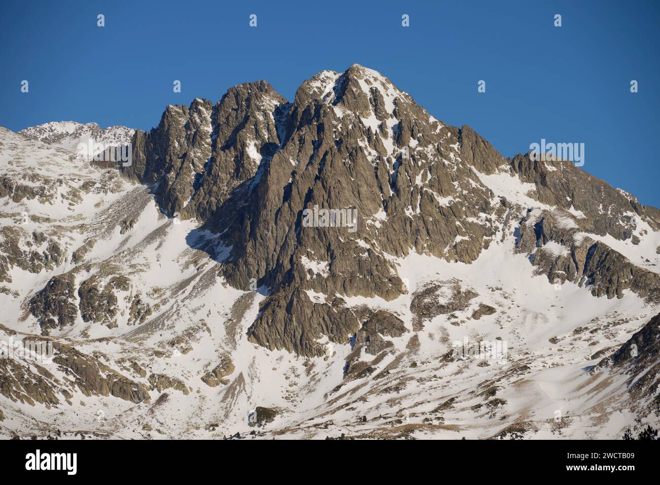 Un'impressionante vetta di montagna ricoperta di neve si erge alto sotto un sereno cielo blu, mostrando la bellezza della natura aspra Foto Stock