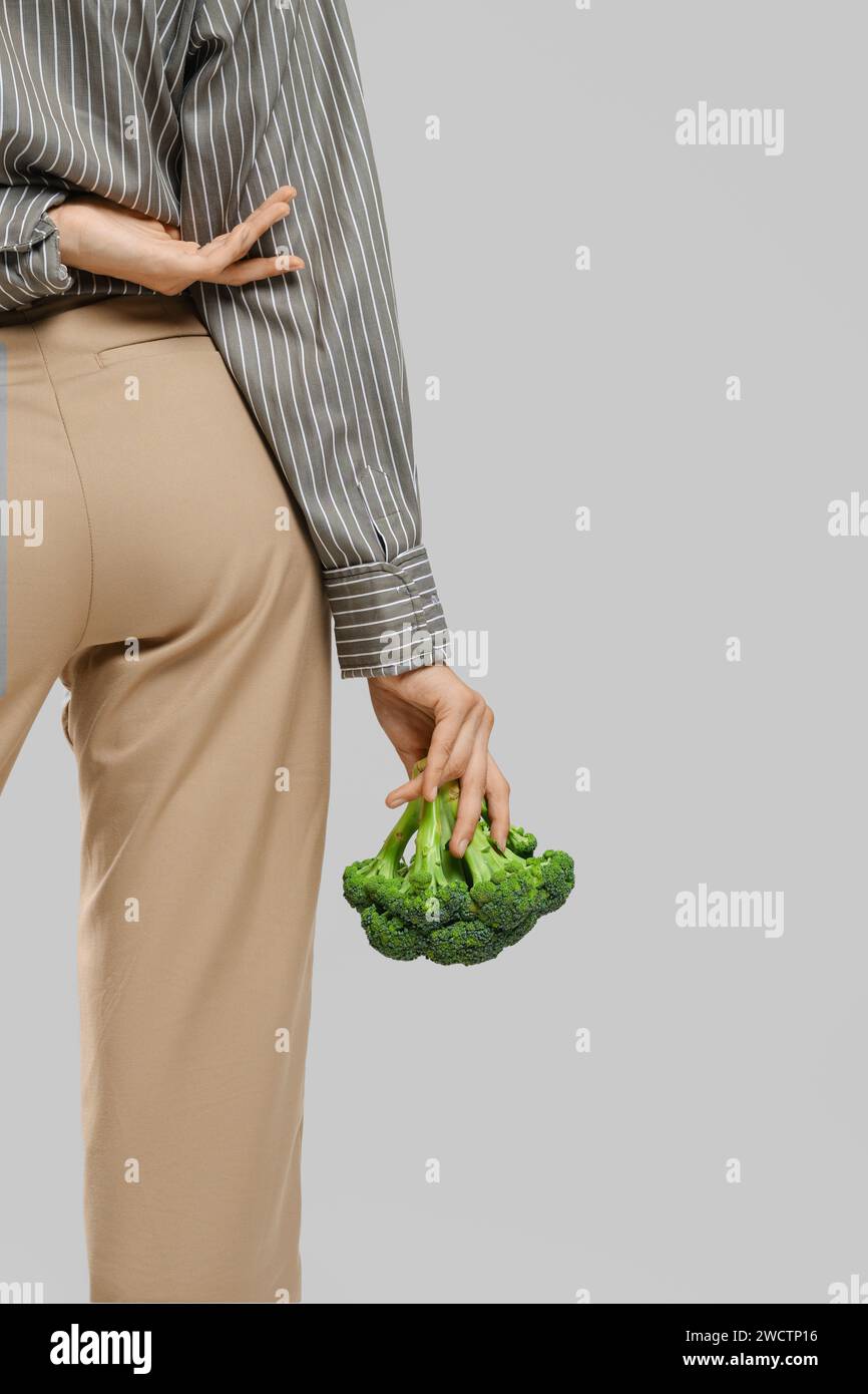 Immagine ritagliata di una giovane donna che tiene i broccoli in mano Foto Stock