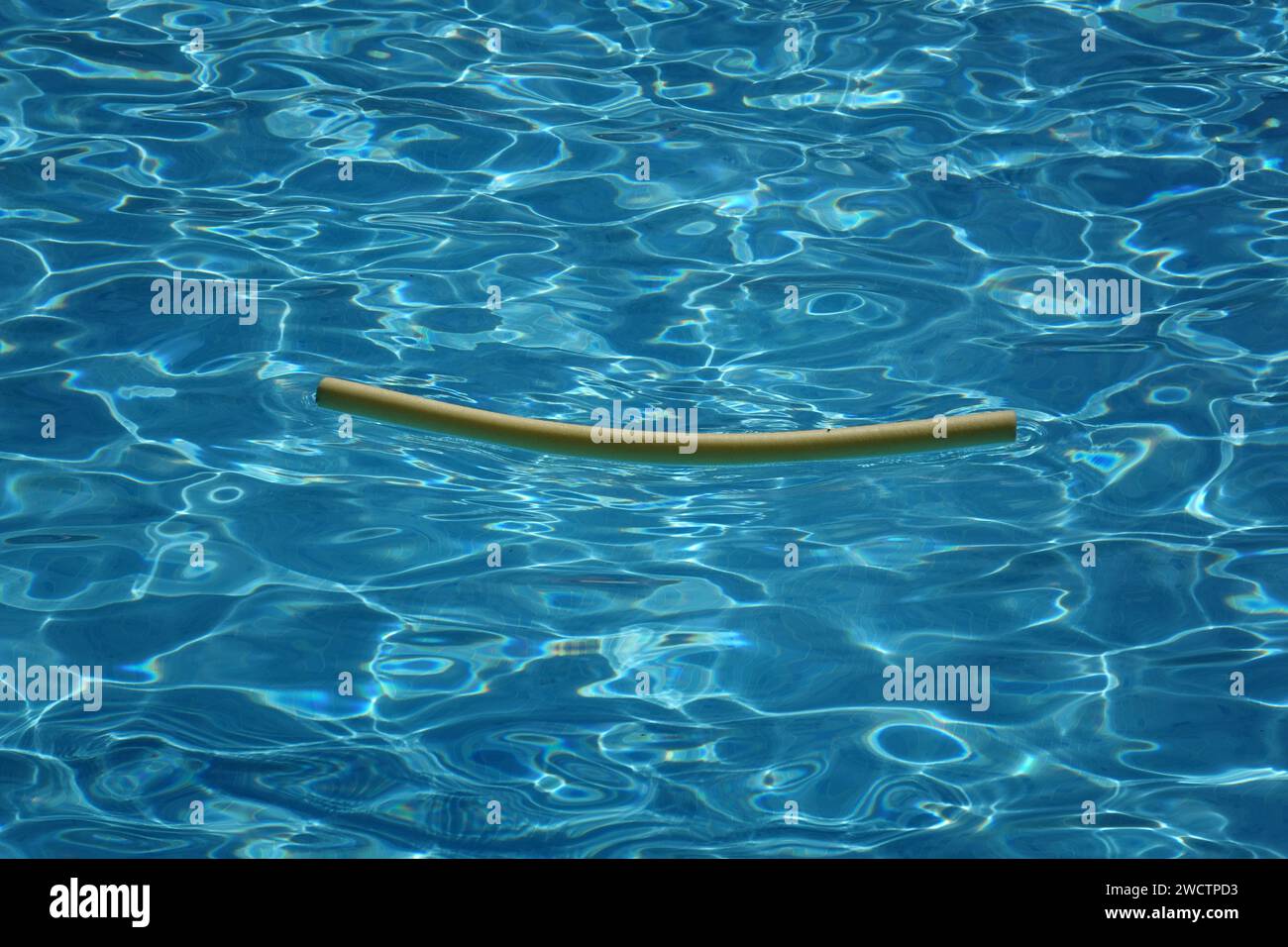 Riflessi in una piscina senza persone e solo un noodle da piscina che vi galleggia, creando un motivo astratto Foto Stock