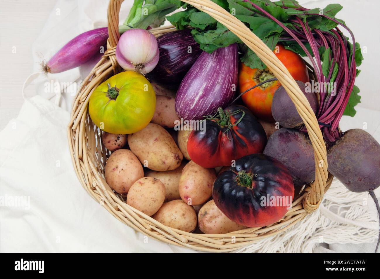 Cestino con varie verdure. Patate, barbabietole, pomodori, scalogni, melanzane. Stile country. Foto Stock