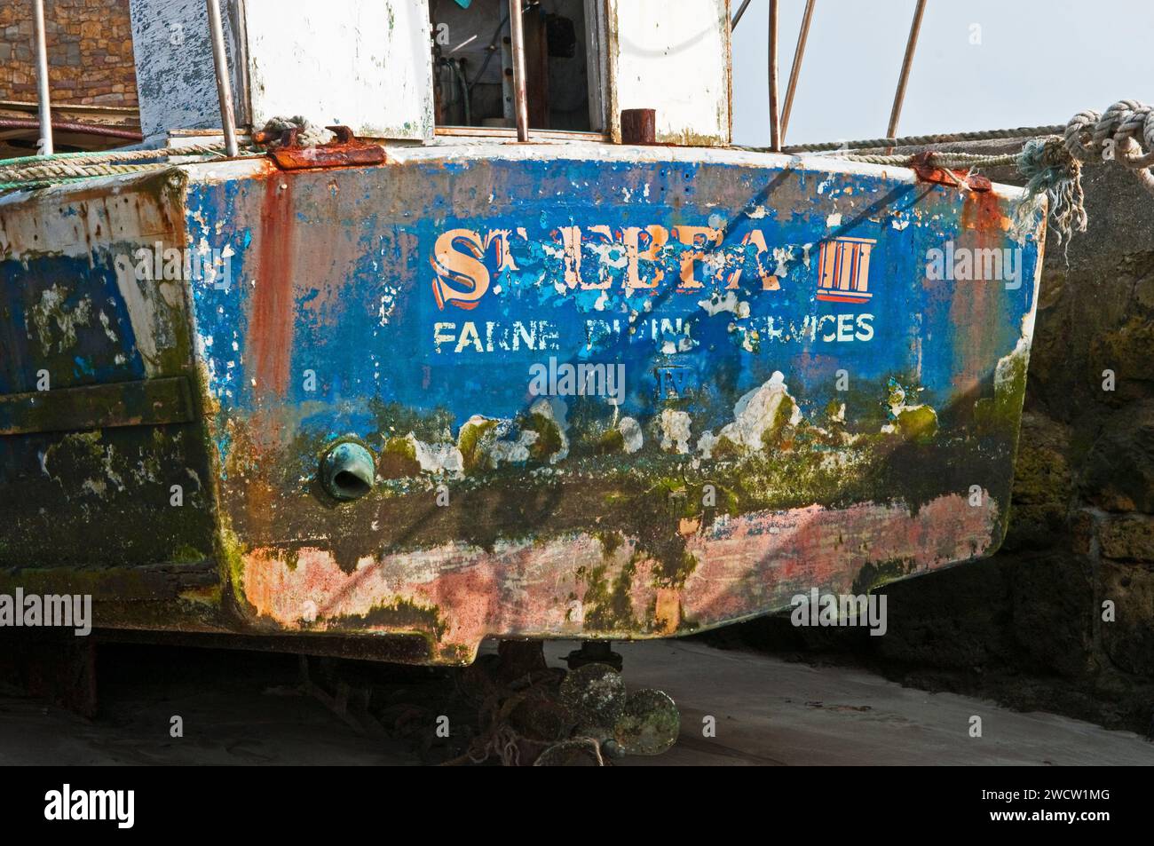 Barca da pesca abbandonata legata al muro del porto di Beadnell sulla costa del Northumberland a marzo. St Ebbs Third e farne Boating Services Foto Stock