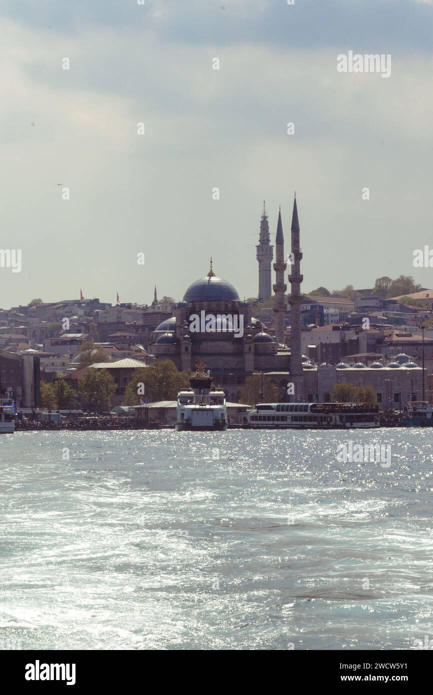 La moschea Yeni Cami catturata da una barca sul Bosforo all'alba, sullo sfondo di un cielo spettacolare a Istanbul, in Turchia Foto Stock