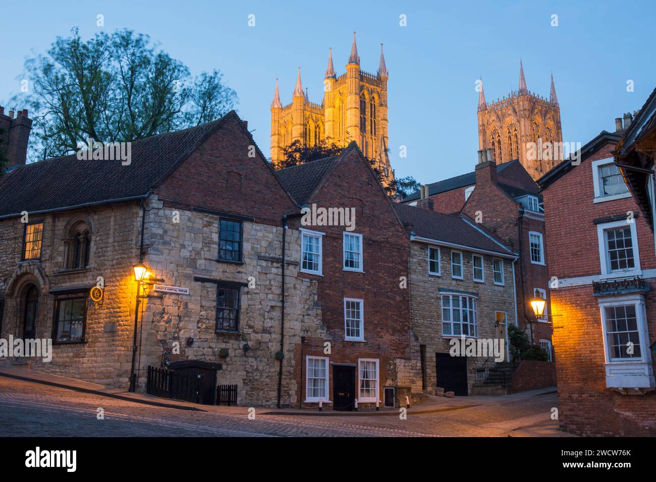 Lincoln, Lincolnshire, Inghilterra. Ammira la ripida collina acciottolata fino alle torri illuminate della cattedrale di Lincoln, al tramonto. Foto Stock