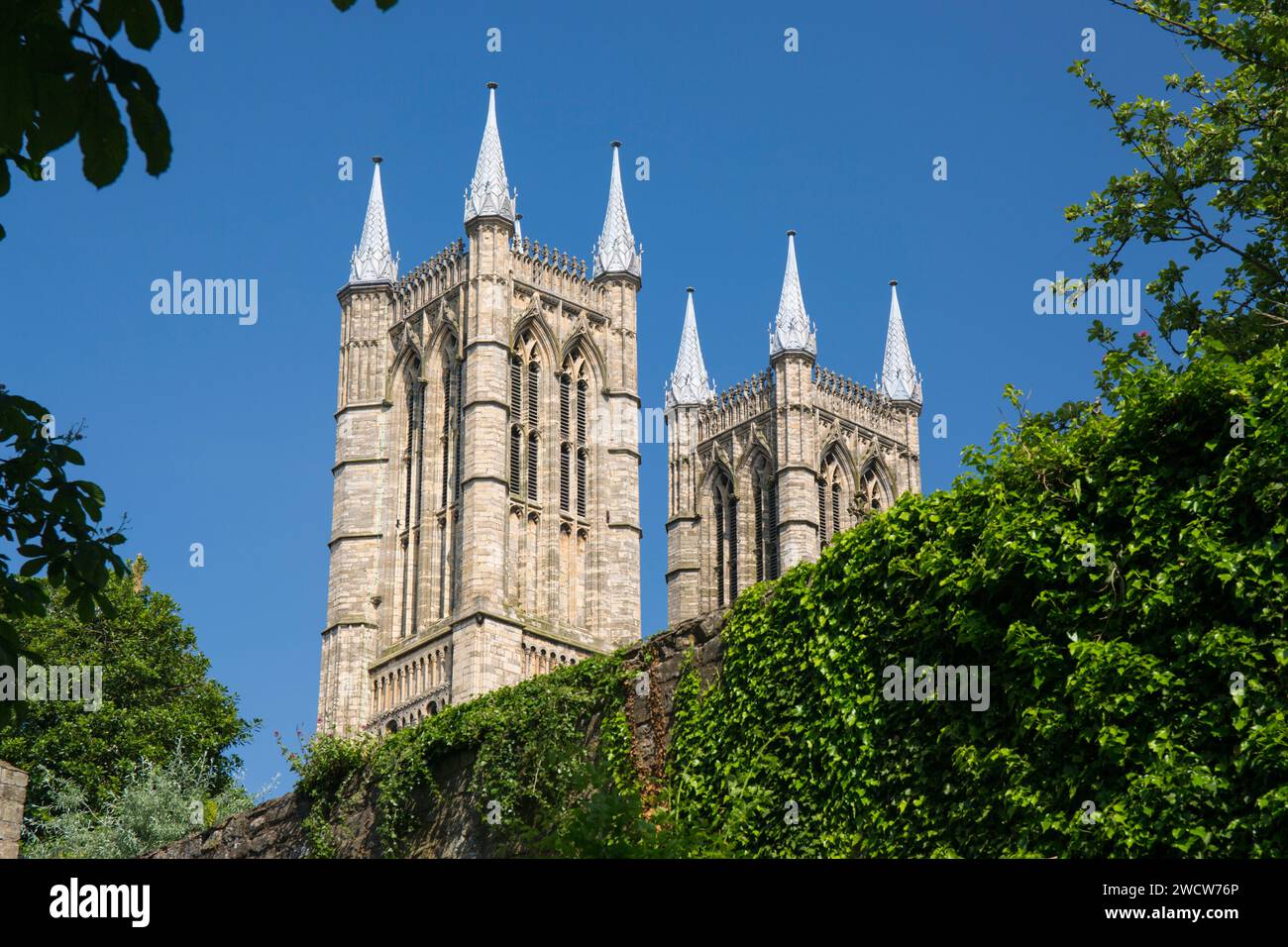 Lincoln, Lincolnshire, Inghilterra. Vista angolare bassa dai giardini del Palazzo Vescovo alle torri occidentali gemelle della Cattedrale di Lincoln. Foto Stock