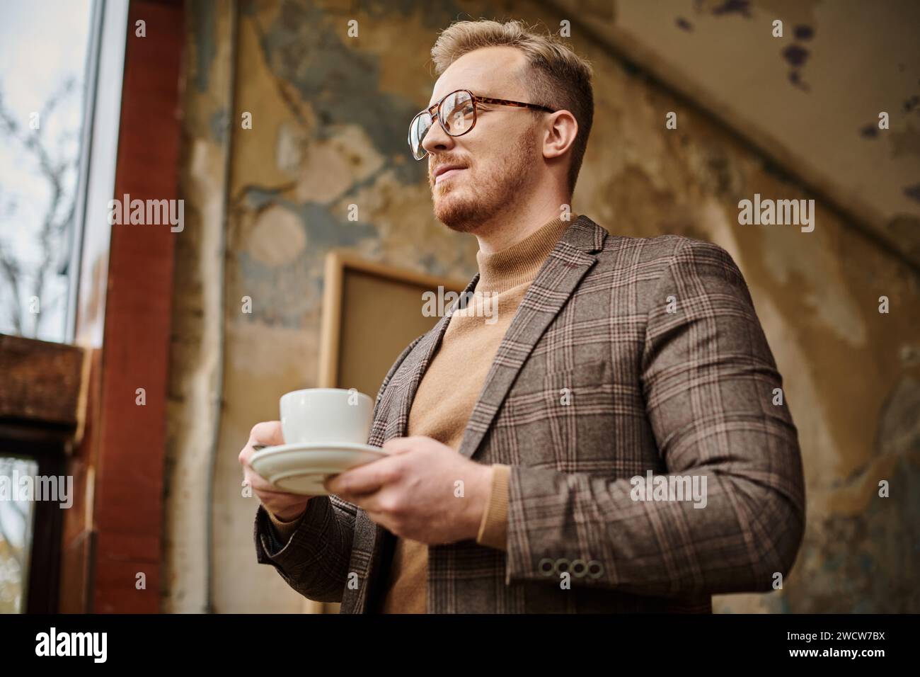 gioioso e sofisticato business leader con bicchieri in elegante abito che beve il suo caffè caldo Foto Stock