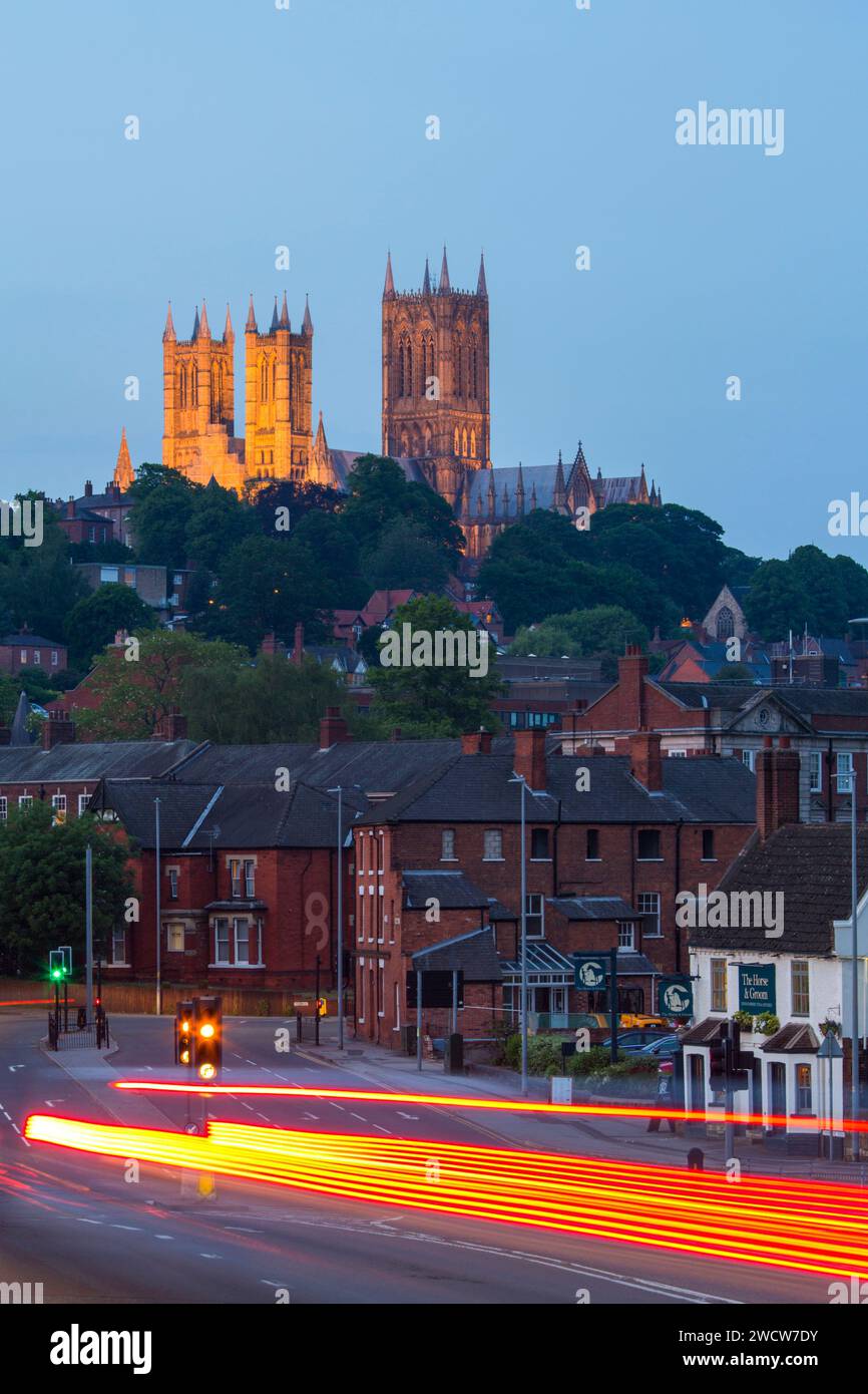 Lincoln, Lincolnshire, Inghilterra. Ammira lungo Brayford Way le torri illuminate della cattedrale di Lincoln, il crepuscolo, i percorsi di luci dei veicoli in primo piano. Foto Stock
