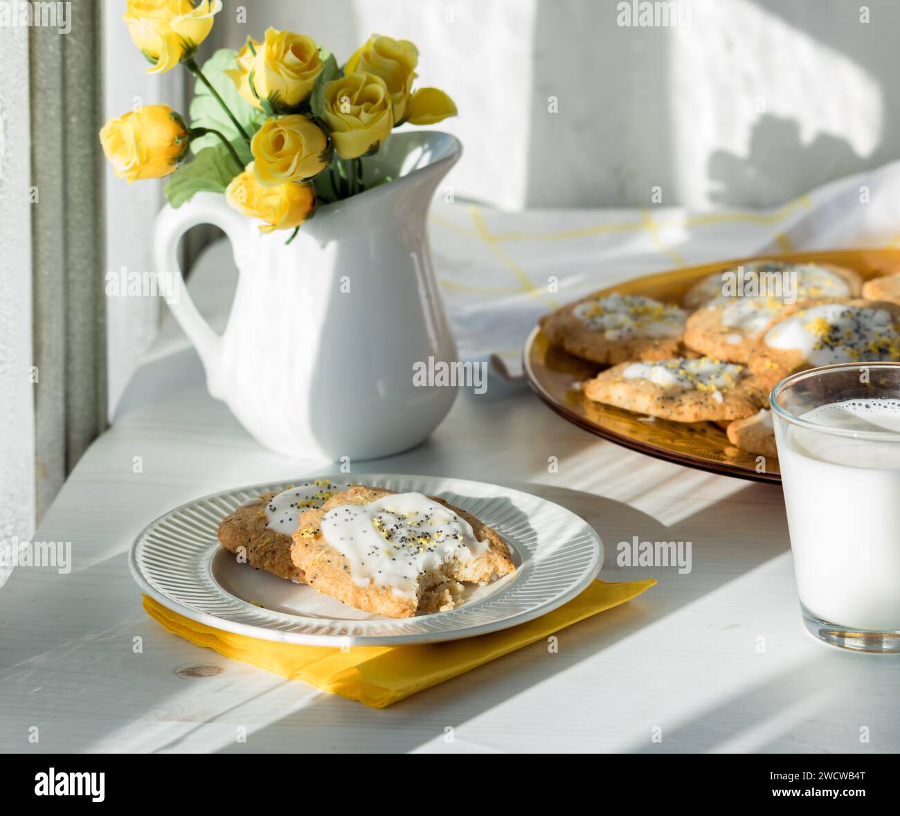 Biscotti fatti in casa con semi di limone e latte su un tavolo alla luce del sole. Foto Stock