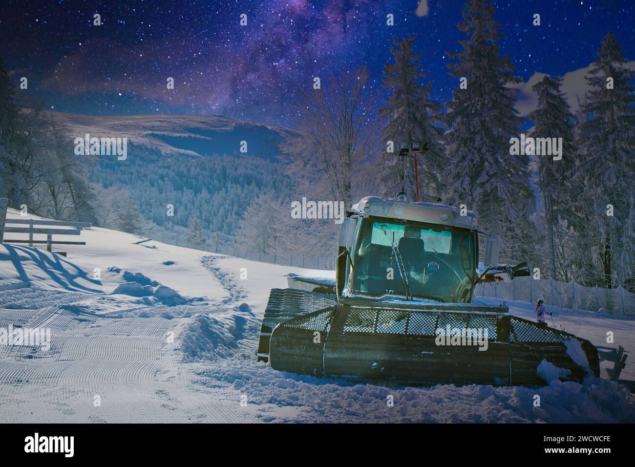 Nel mezzo di un paesaggio selvaggio, un robusto bulldozer si trova in posizione sicura su una strada ricoperta di neve Foto Stock