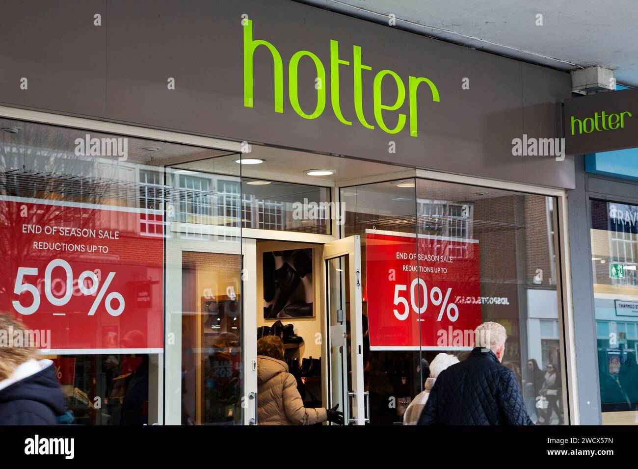 Fai acquisti nel negozio di scarpe "Hot" di Exeter, Devon, Regno Unito, con cartelli rossi di fine stagione; cartelli di vendita nella finestra anteriore Foto Stock
