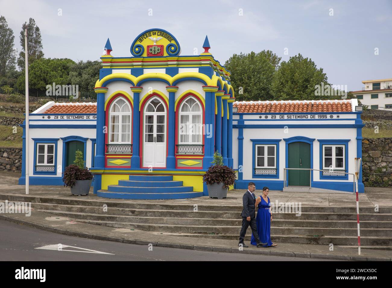 Portogallo, arcipelago delle Azzorre, isola di Terceira, Praia da Vitoria, coppia vestita al meglio della domenica davanti all'Imperio do Divino Espirito Santo da Caridade, una cappella multicolore dedicata allo spirito santo Foto Stock